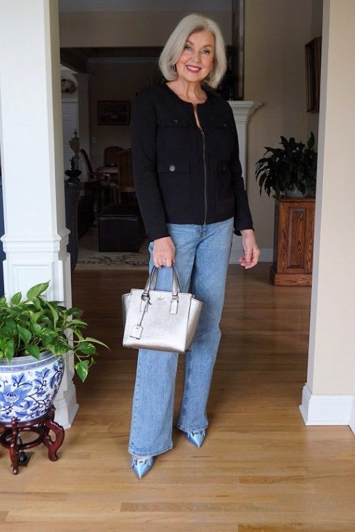 Woman over 50 wearing black blazer with blue jeans and white handbag, everyday casual outfit idea