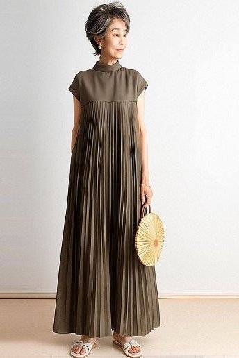 Older woman wearing an olive pleated maxi dress with sandals and a round bag