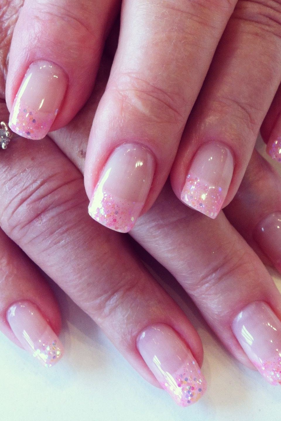 Pink glitter ombre nails on mature woman's hands