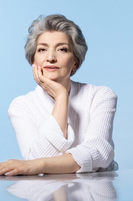 Classic gray pixie bob, posed portrait, light blue background, timeless hairstyle for women over 70