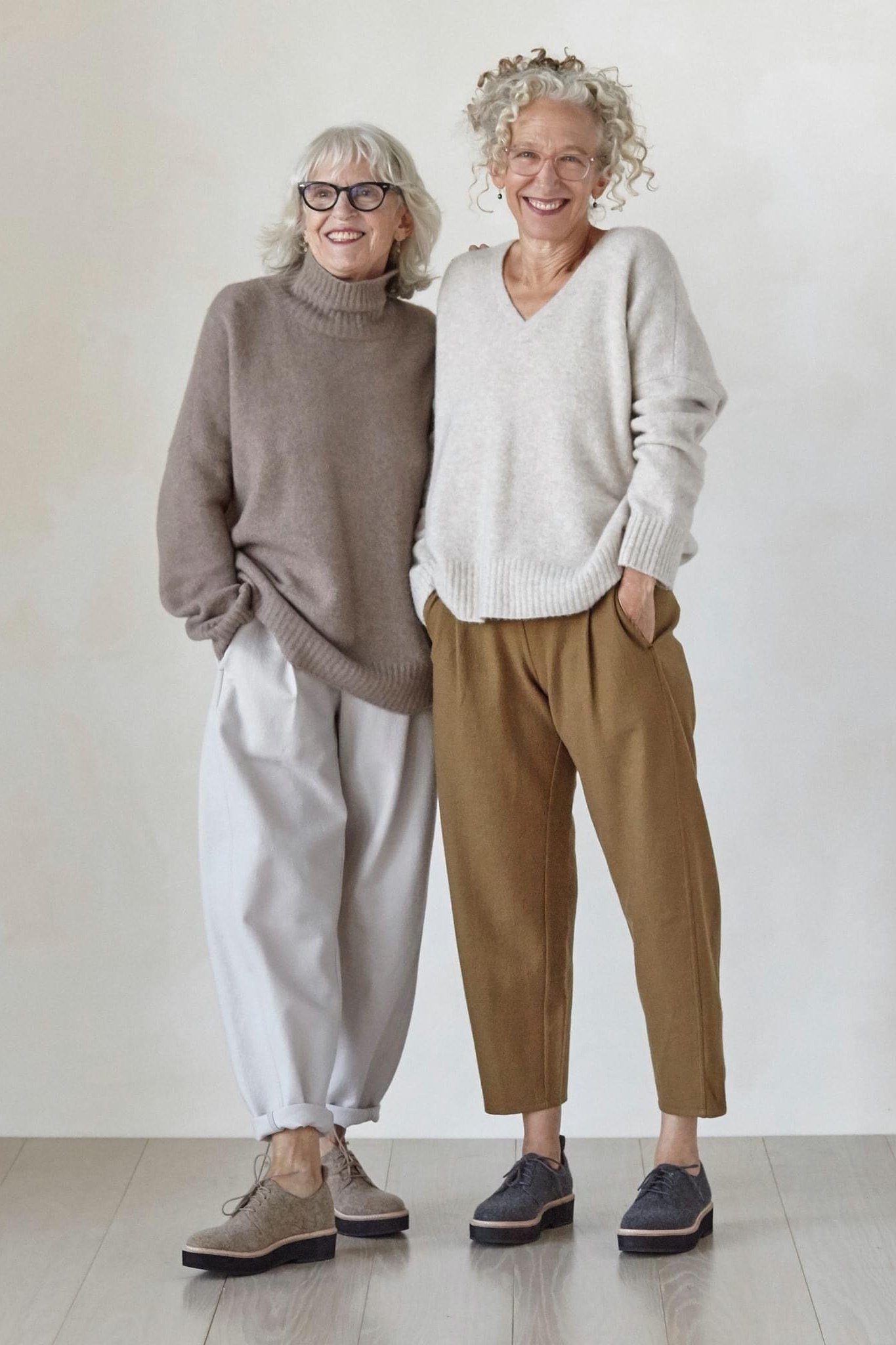 Woman over 50 wearing Two women in slouchy sweaters and joggers, studio shot.