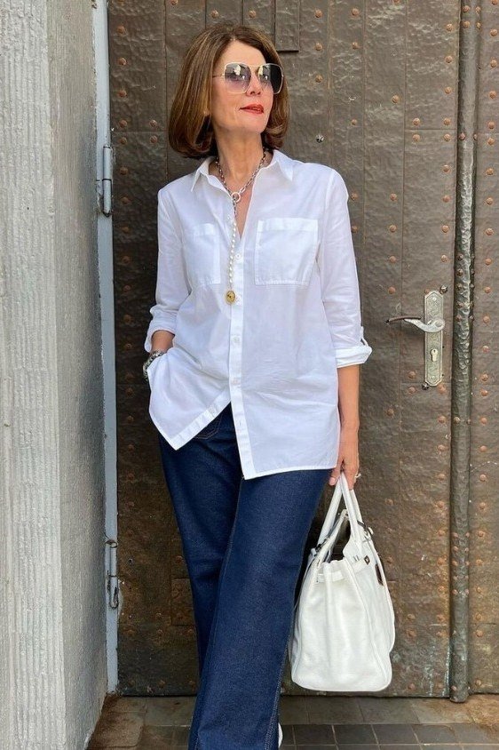 Older woman wearing a white shirt with dark blue jeans and a white bag