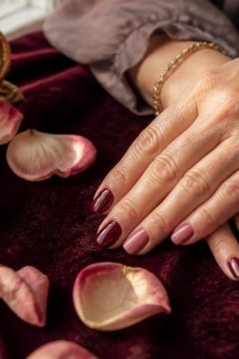 Mauve nails on mature hands with rose petals