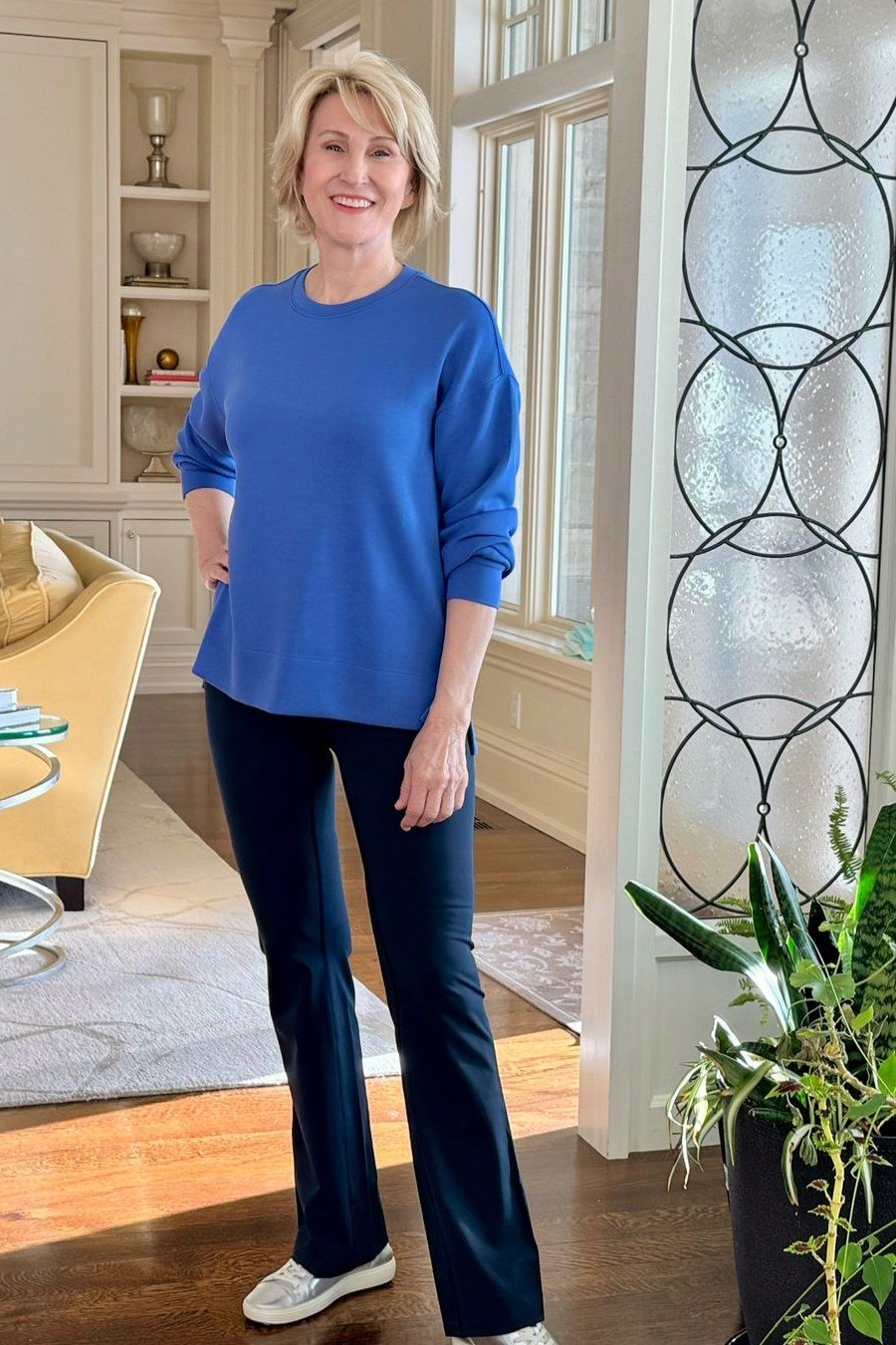 Woman over 50 wearing blue sweatshirt with dark wide-leg pants, everyday casual outfit idea