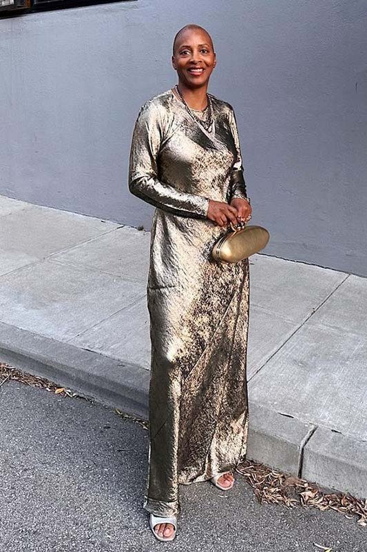 Metallic gold pleated jumpsuit with a gold clutch and heeled sandals, glamorous weekend outfit for women over 40
