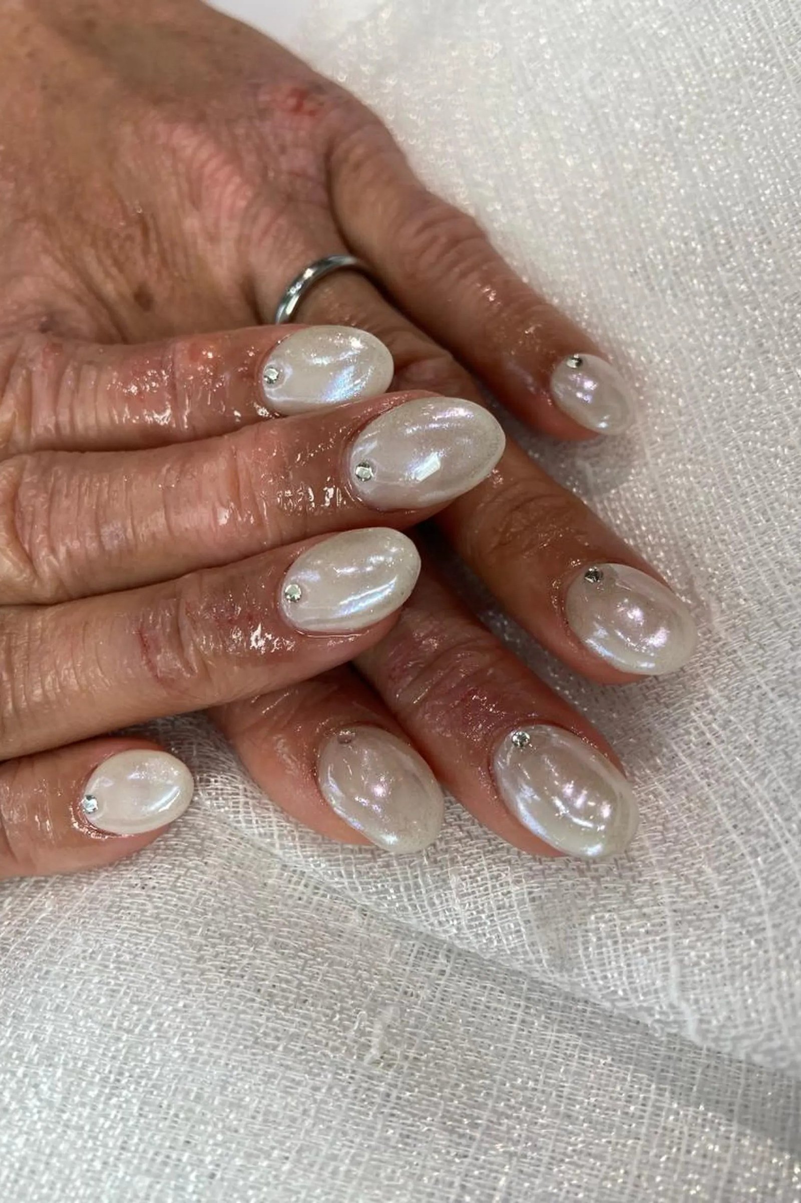 Pearly white marble nails on elderly hands