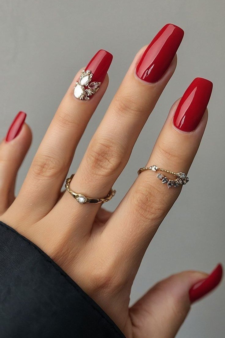 Bright red almond nails with a white daisy accent nail, glossy playful fall look.