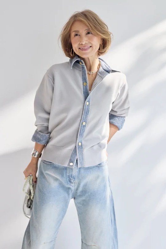 Woman over 60 wearing light gray shirt, light jeans, studio