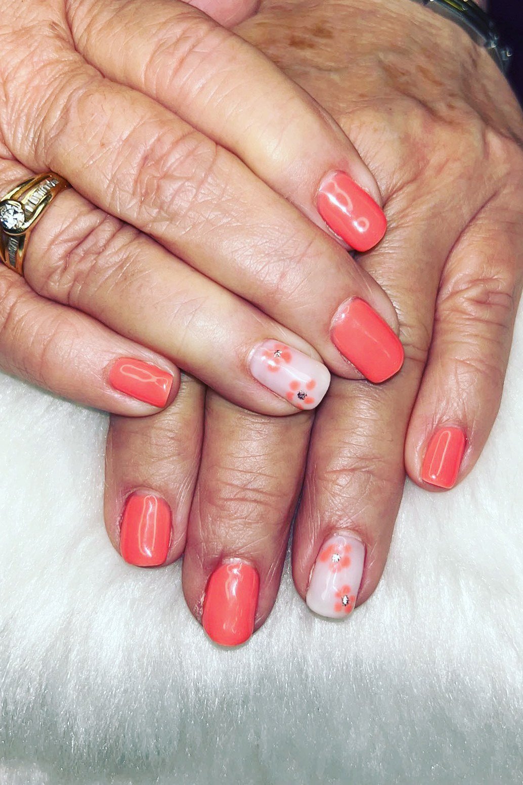 Coral gel nails with floral accents for mature hands