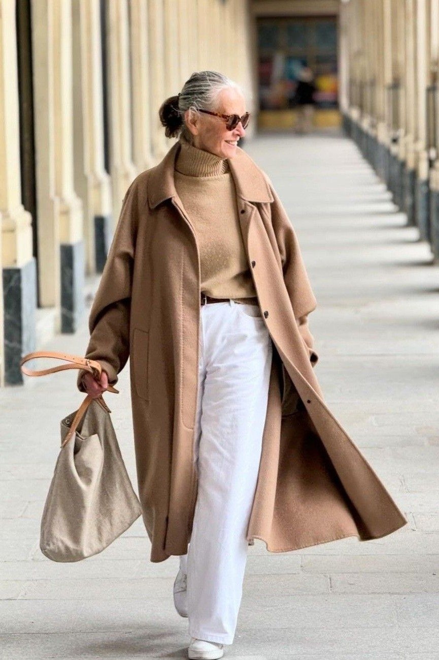 Effortlessly chic fall outfit for women over 60: camel coat over tan turtleneck and white trousers