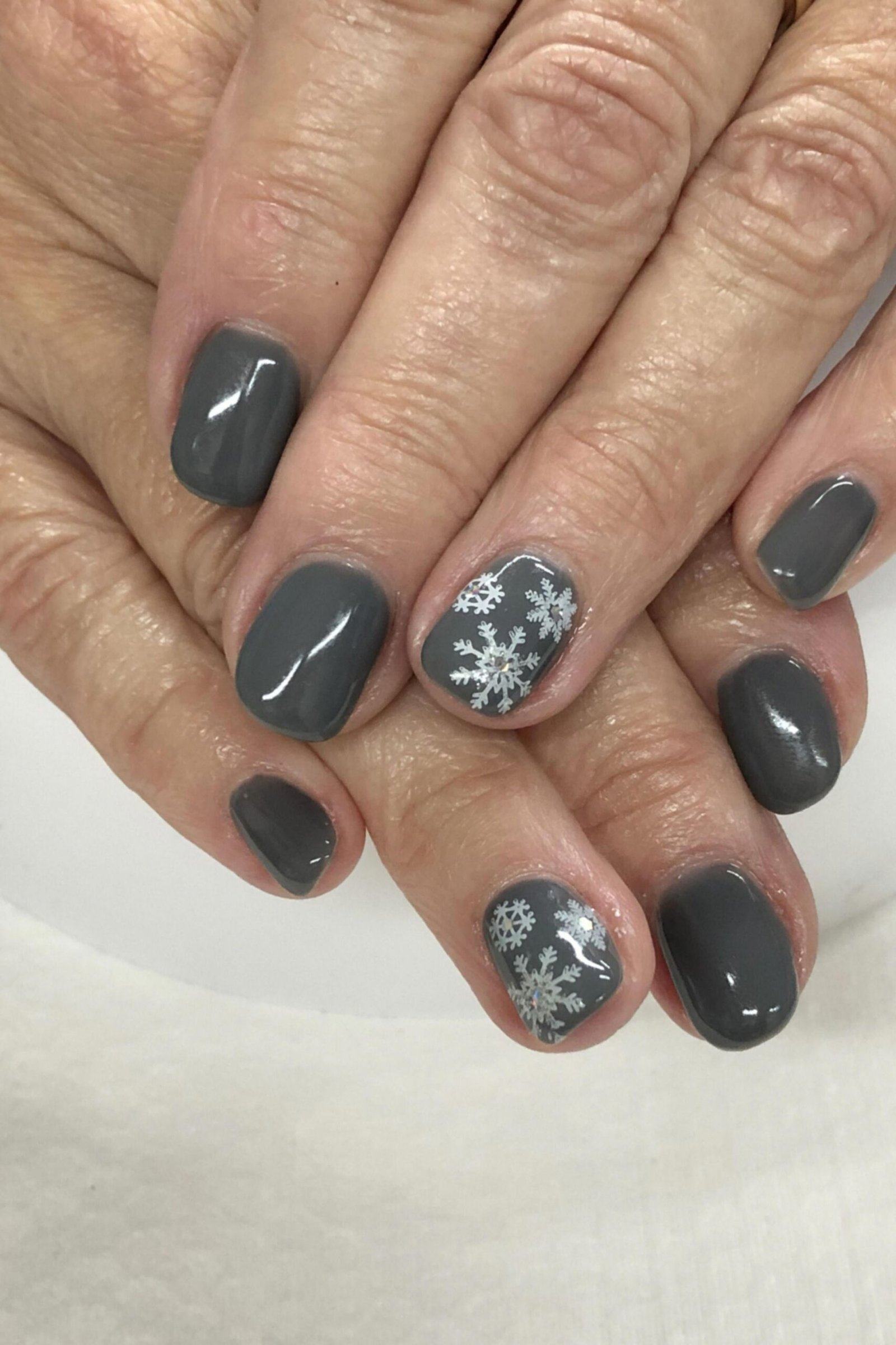 charcoal gray with silver snowflake accent nails - winter nail trend for older women