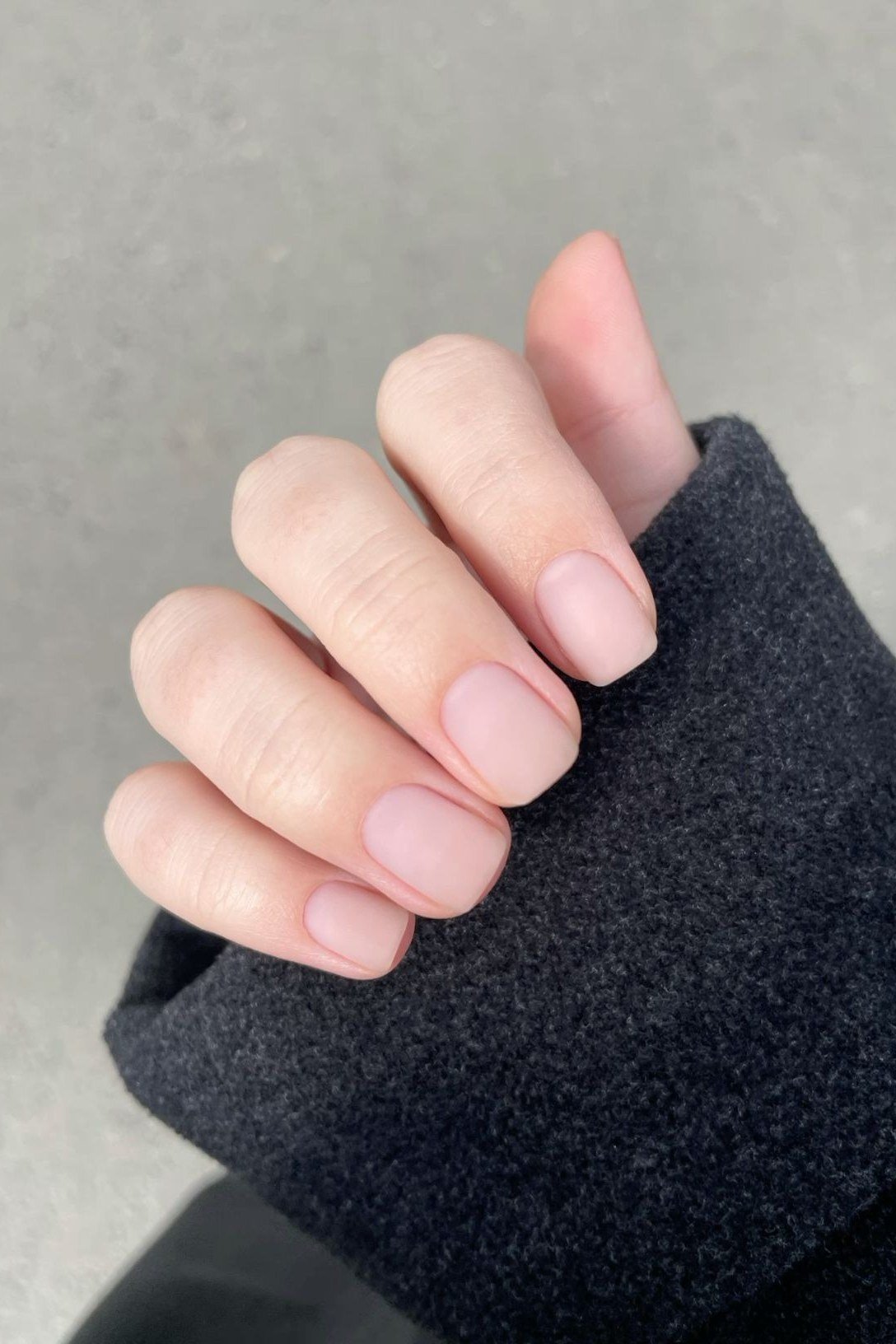 Nude nails with hand in dark sleeve