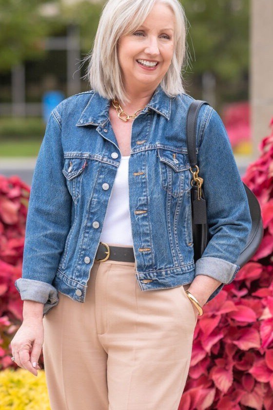 Denim jacket with white top and khaki trousers, pink flowers behind