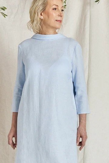 Pale blue tunic dress, older blonde woman, draped curtain