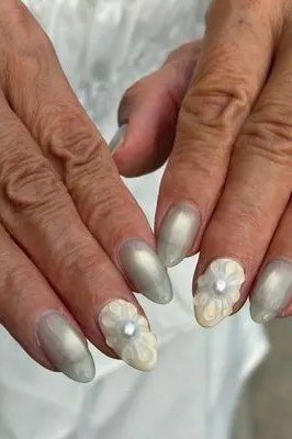 Silver grey nails with pearl accents on elderly hands