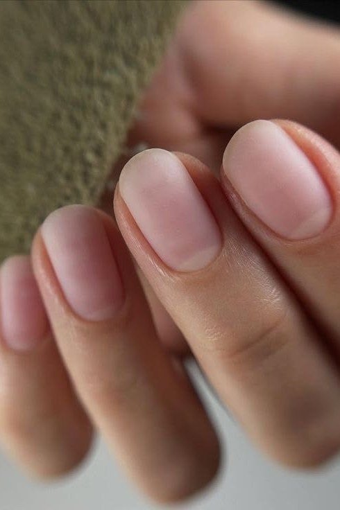 Soft nude nails close-up with green knit
