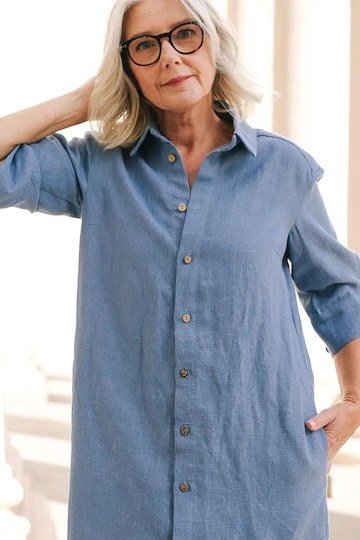 Woman in a chambray button-front shirt dress, leaning against a wall - summer dress for women over 50