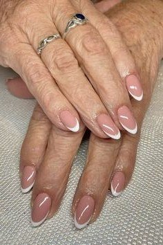 Pink nude nails on mature hands with rings, sophisticated nail design for women over 50