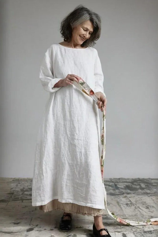 Woman in a white long-sleeve linen maxi dress with a patterned belt, studio shot - summer dress for women over 50