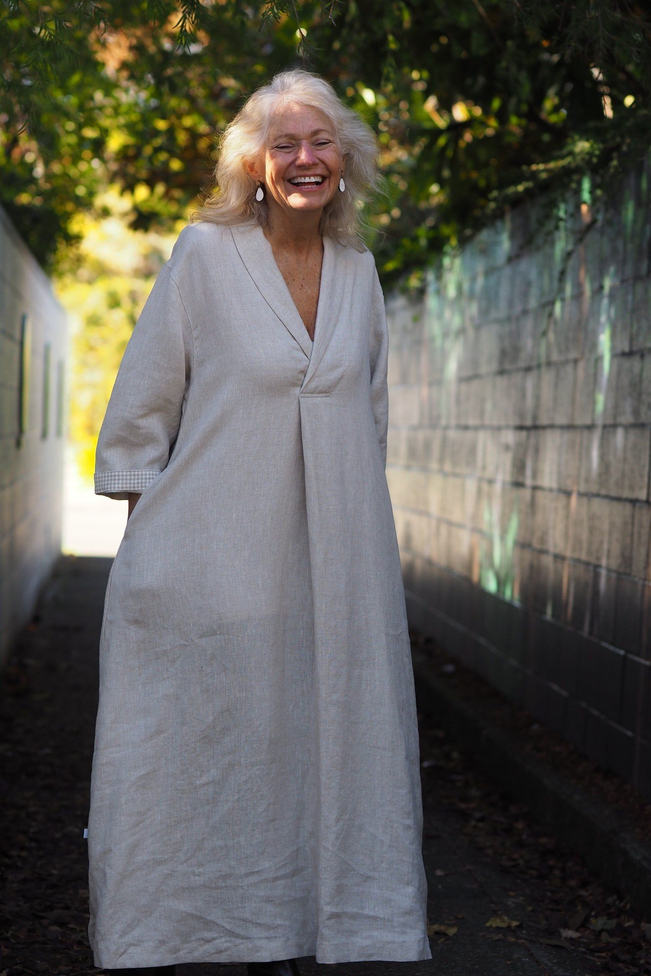 Grey wrap maxi dress, older grey-haired woman, garden wall