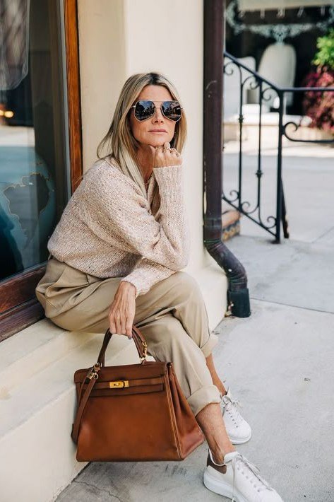 Beige knit sweater with beige trousers, white sneakers, and a tan handbag, relaxed weekend outfit for women over 40