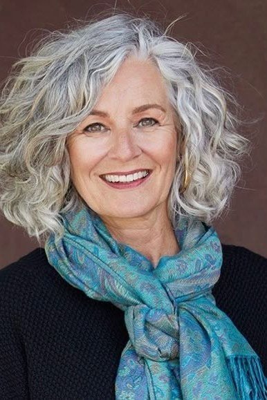 grey curly layered bob, front view, smiling — chin-length layered bob hairstyle for women over 50
