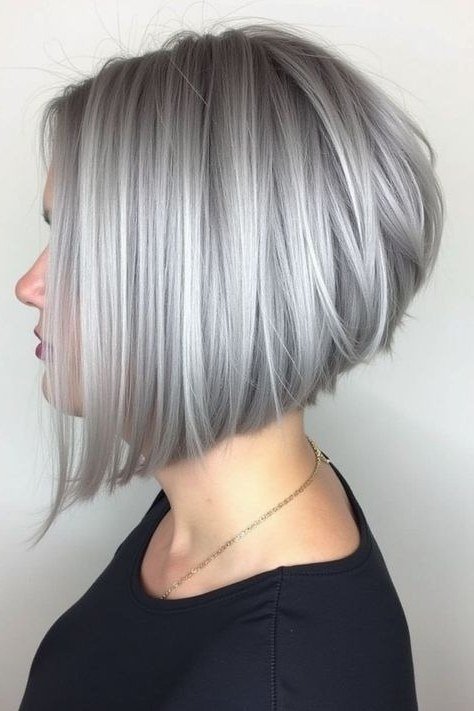 Silver-white dramatic angled asymmetric bob with stacked back, one side sweeping past chin