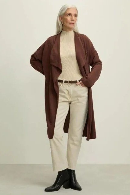 Woman wearing a chocolate brown long cardigan over a cream top and cream pants with black boots