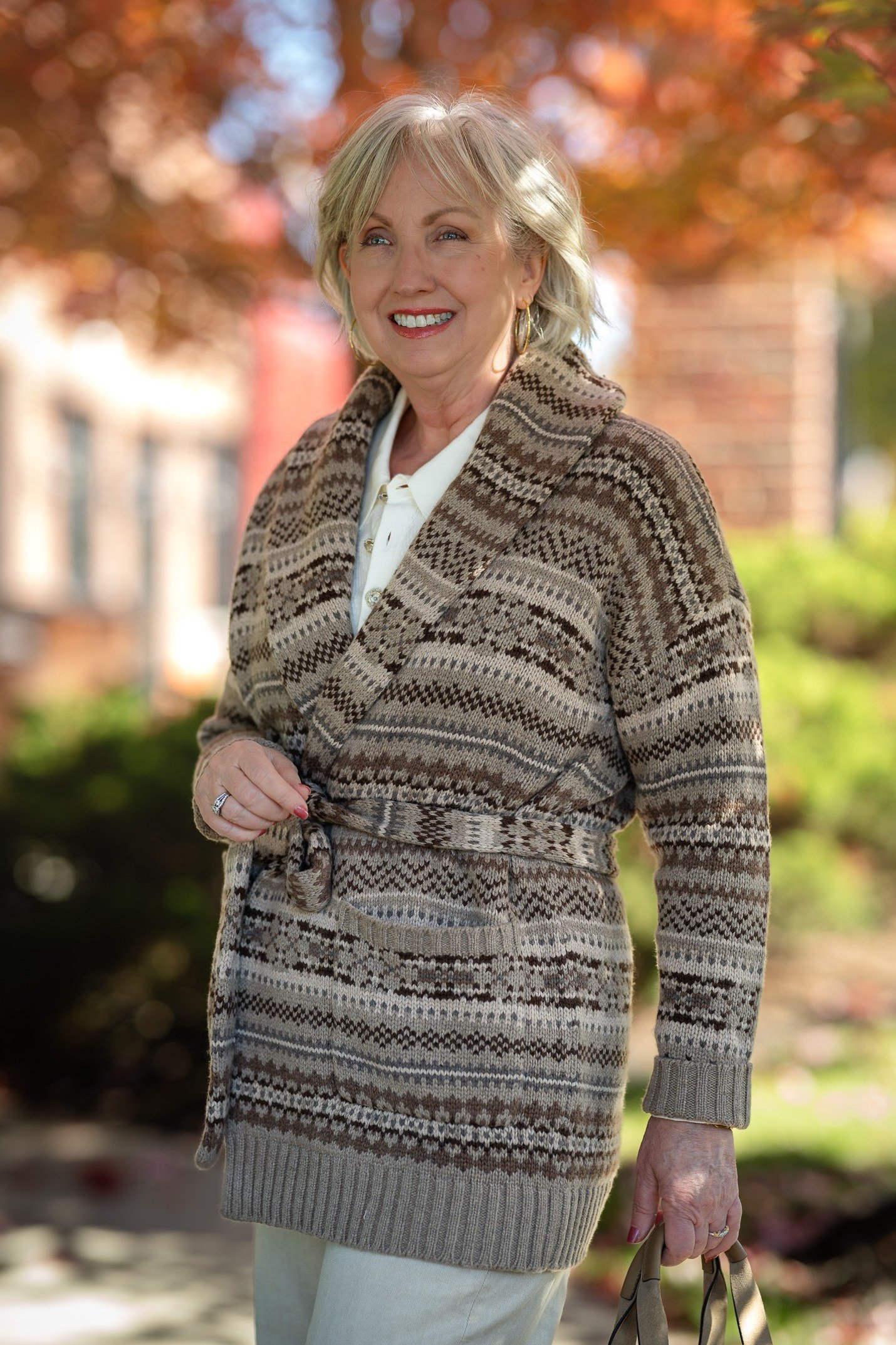 Older woman in an autumn setting wearing a brown fair-isle patterned cardigan