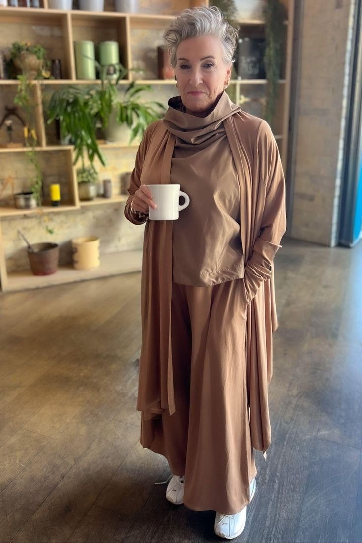 Woman in a cafe wearing a camel long cardigan over a matching caramel knit set
