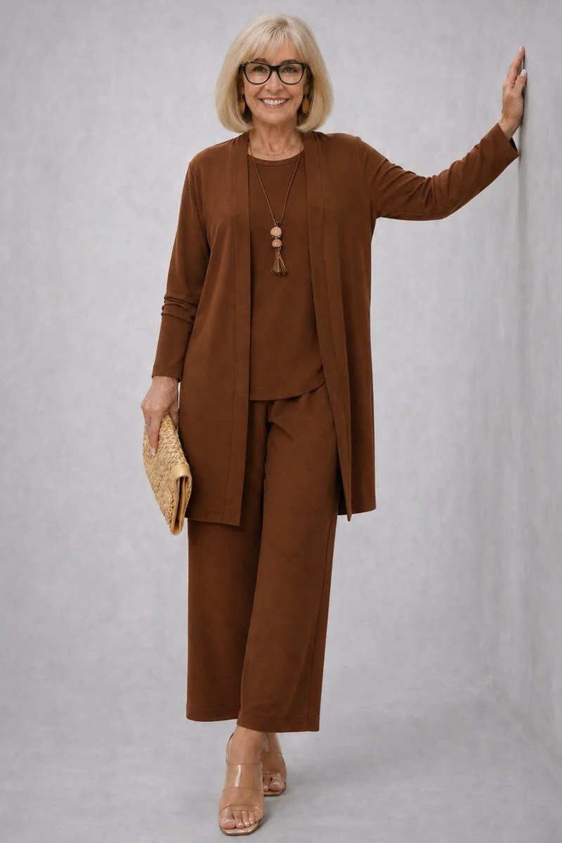 Older blonde woman in a studio wearing a chocolate brown cardigan set