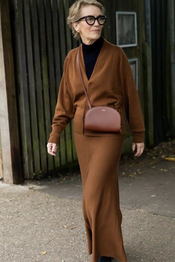 Woman with glasses on a street wearing a camel wrap cardigan with a matching knit skirt set