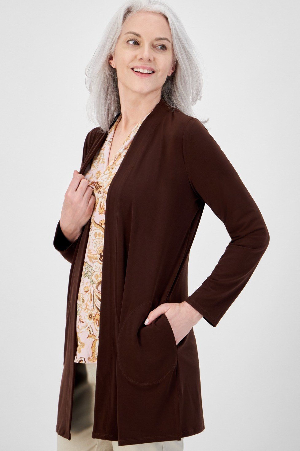 Older woman in a studio wearing a dark brown open cardigan over a floral top