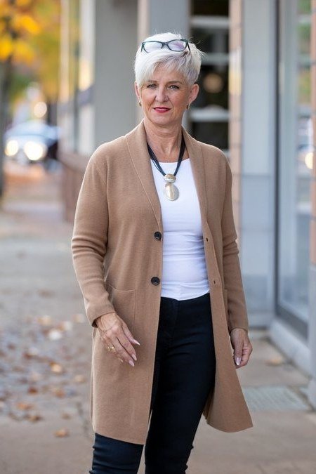 Older woman on a street wearing a camel long cardigan over a white top and black pants