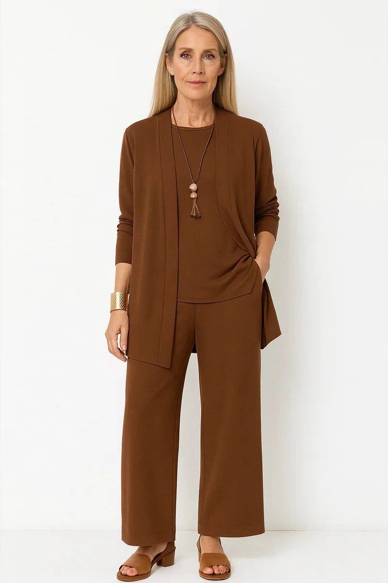 Older blonde woman in a studio wearing a chocolate brown cardigan set