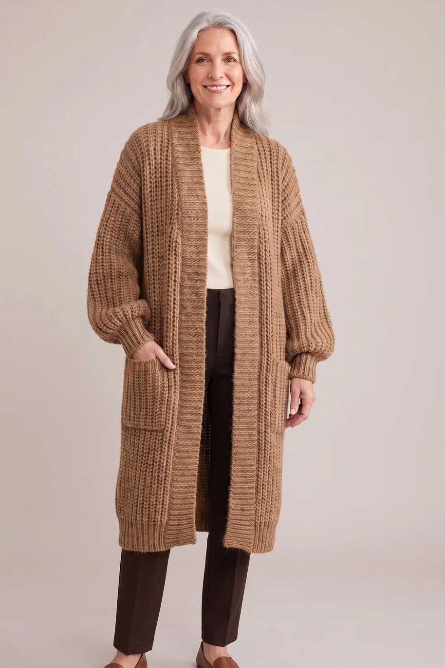 Older woman in a studio wearing a camel chunky knit cardigan