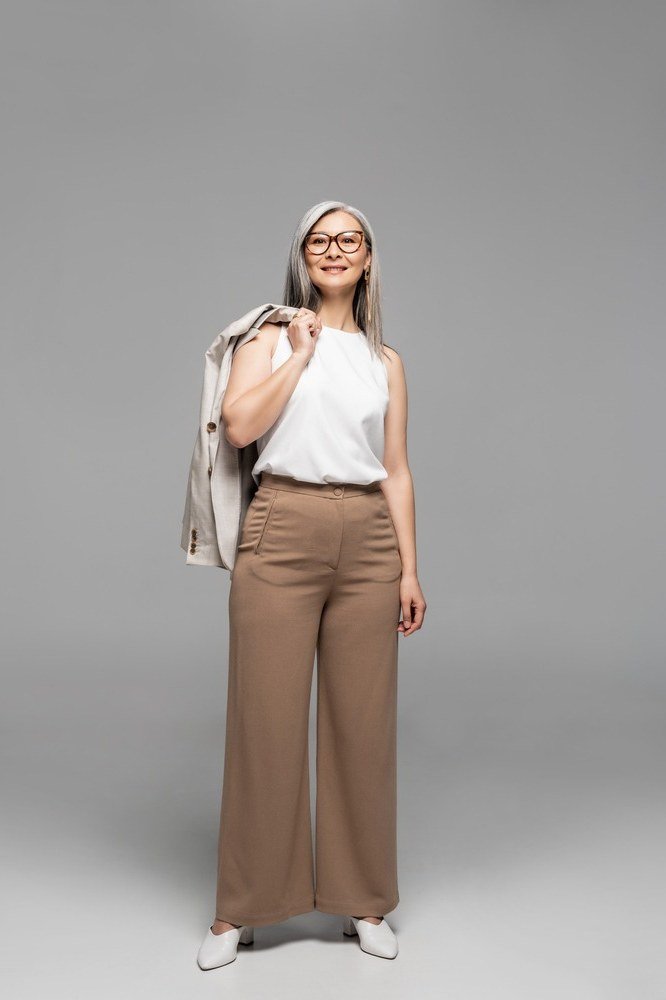 White sleeveless blouse with tan wide trousers for women over 60