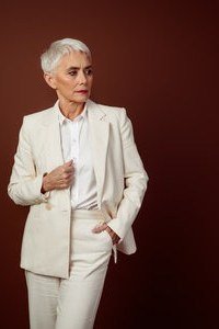 Cream pantsuit with dark red backdrop, white hair