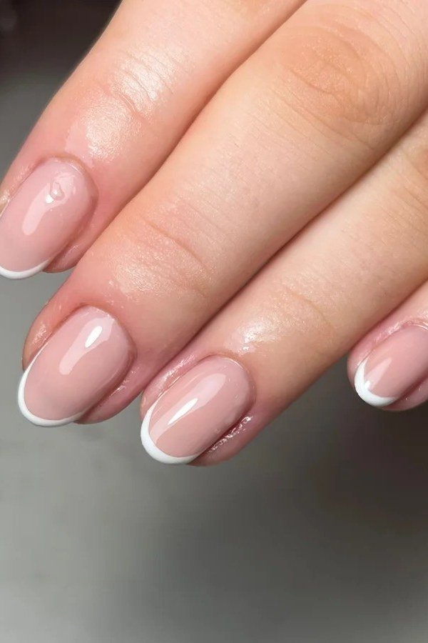 Classic white French tips on short almond nails with glossy builder gel finish for women over 50