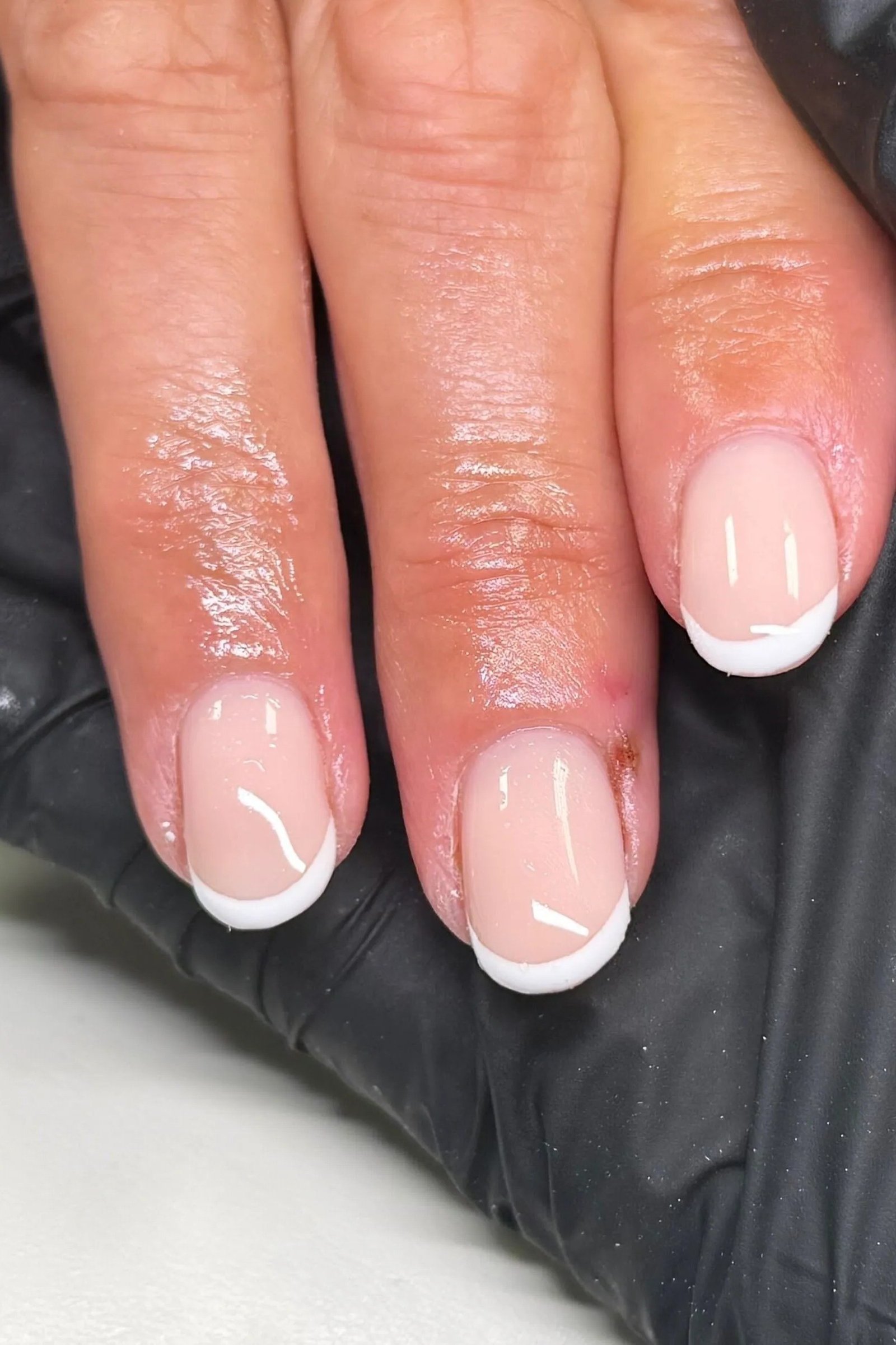 Short square French on mature tech hand with black glove backdrop, builder gel