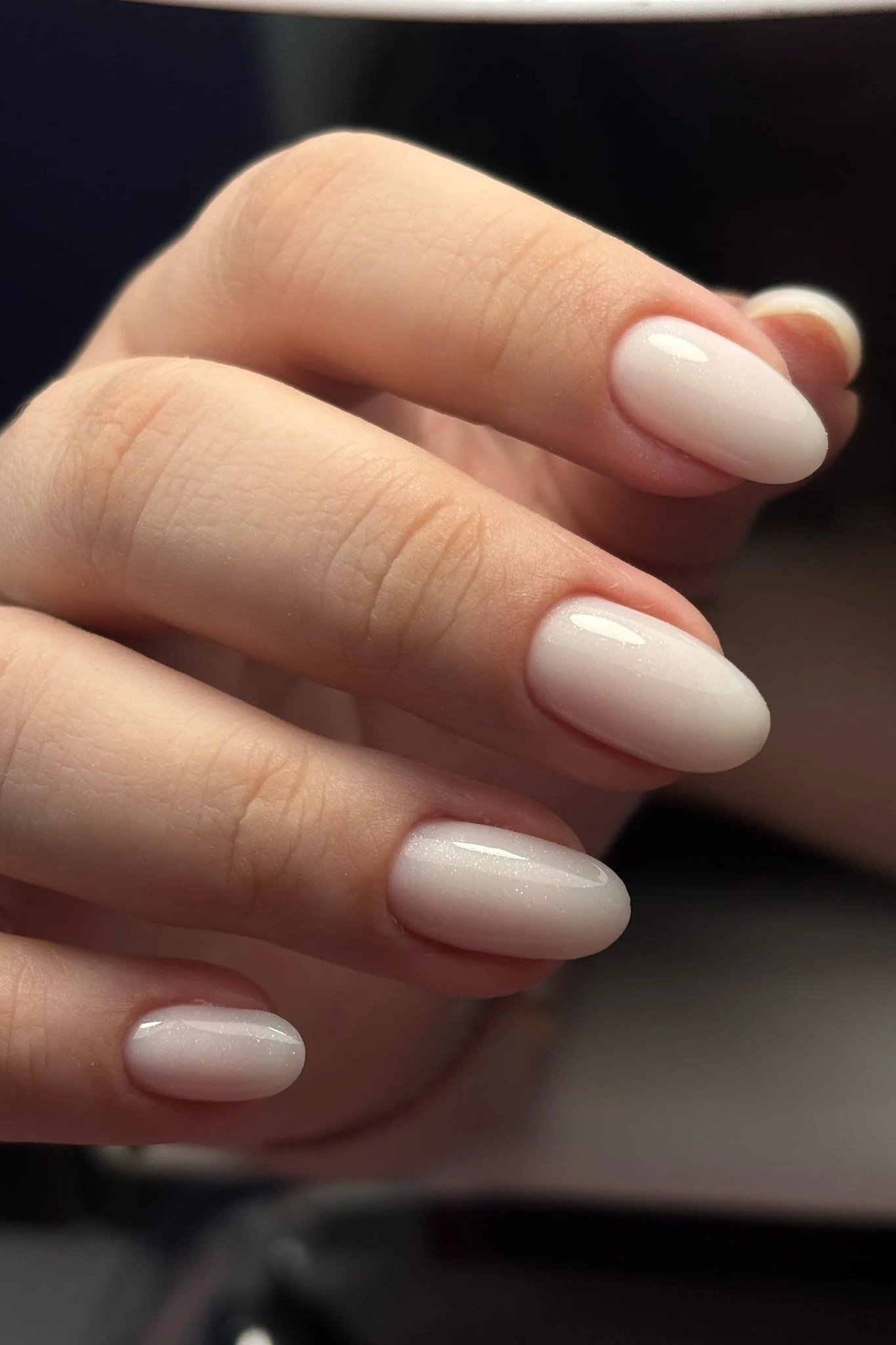 Milky white oval nails with high shine on dark background, builder gel over 50