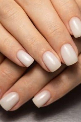 White short square nails, hands crossed on dark table, builder gel manicure