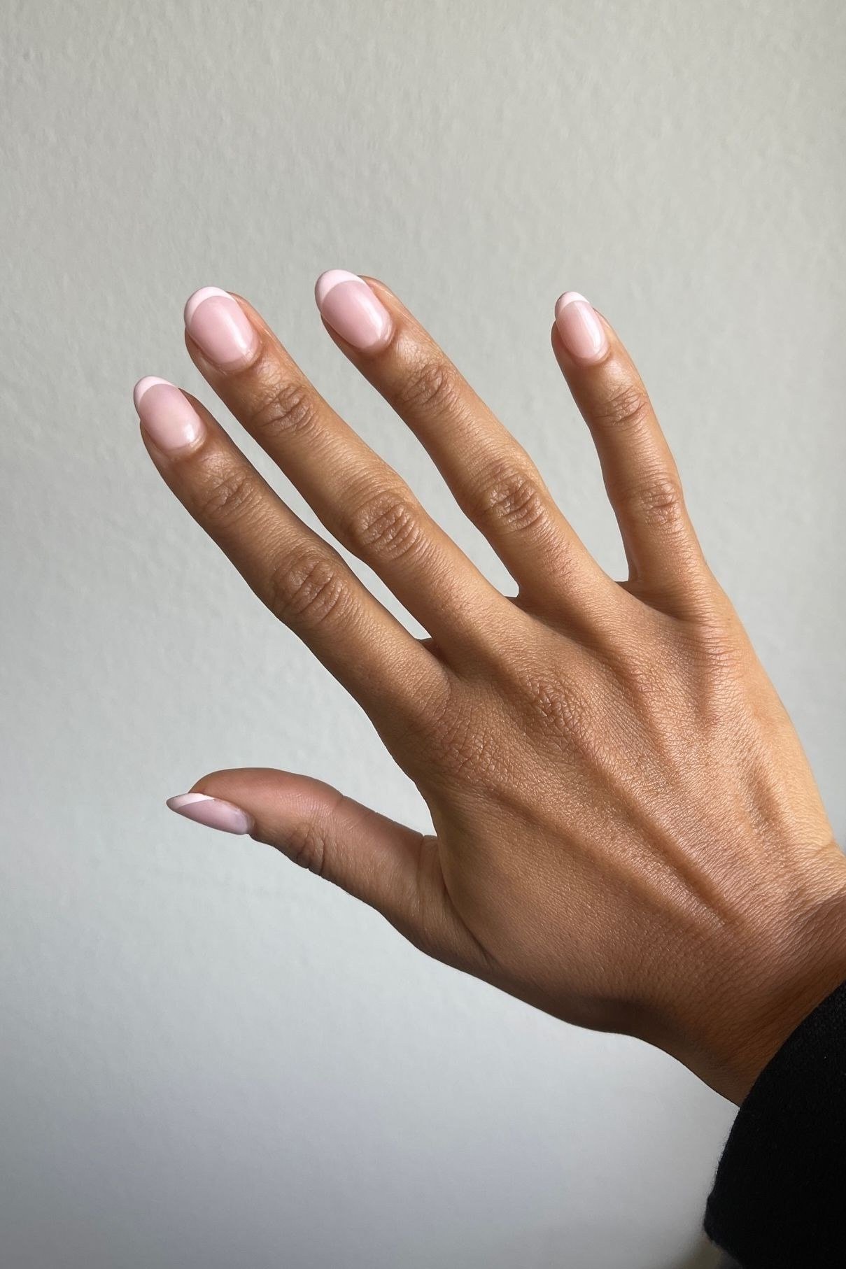 Nude short nails on dark skin hand with neutral wall, builder gel over 50