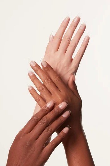 Nude builder gel nails on two hands of different skin tones together
