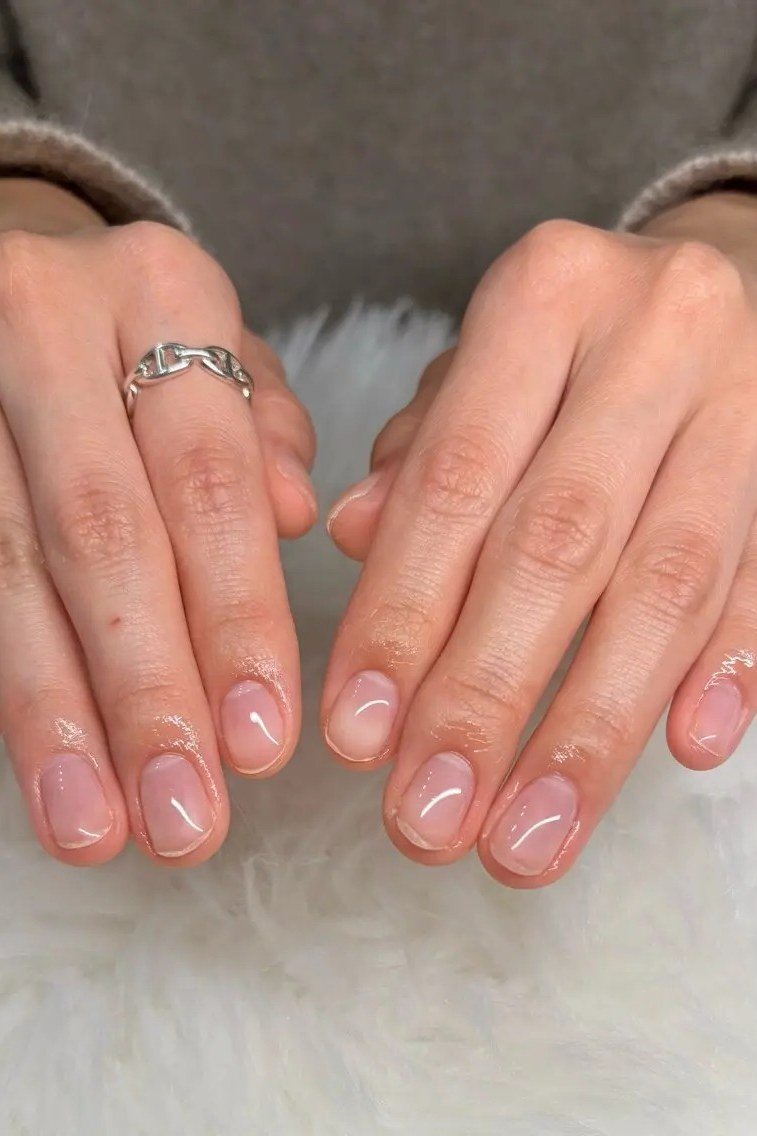 Nude builder gel nails with rings, two hands on white fur