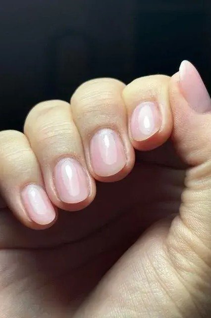 Pink short nails on dark background, glossy builder gel for women over 50
