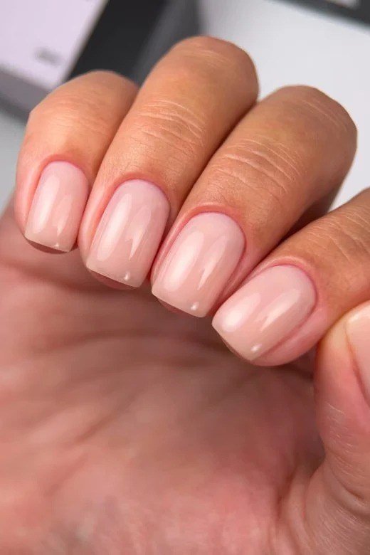 Pink-nude almond nails close-up, natural builder gel overlay over 50