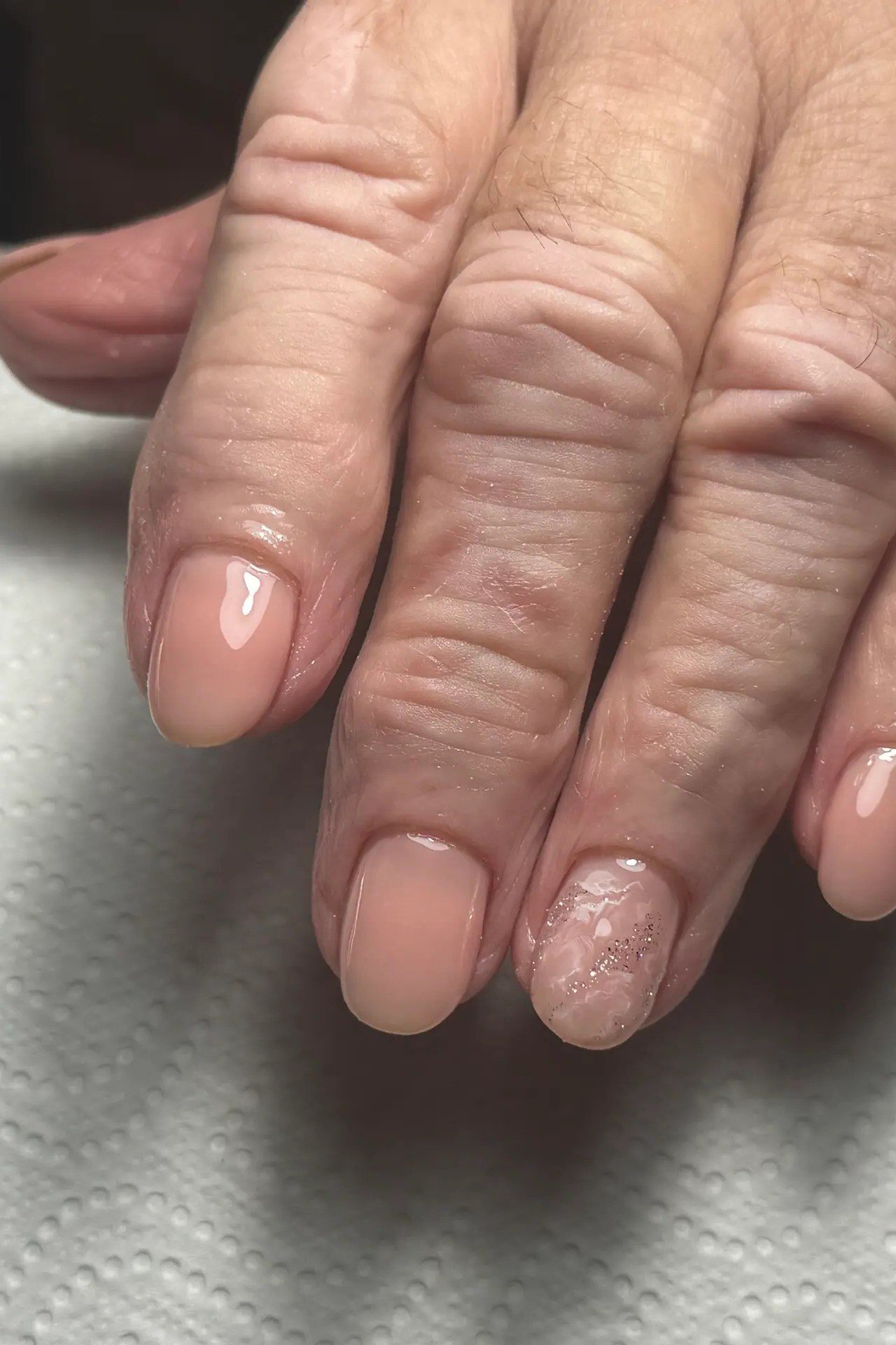 Natural nude builder gel overlay on visibly aging hand, women over 50