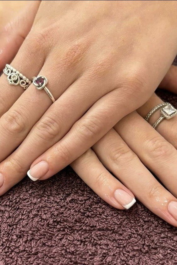 Short French on mature crossed hands with rings, builder gel over 50