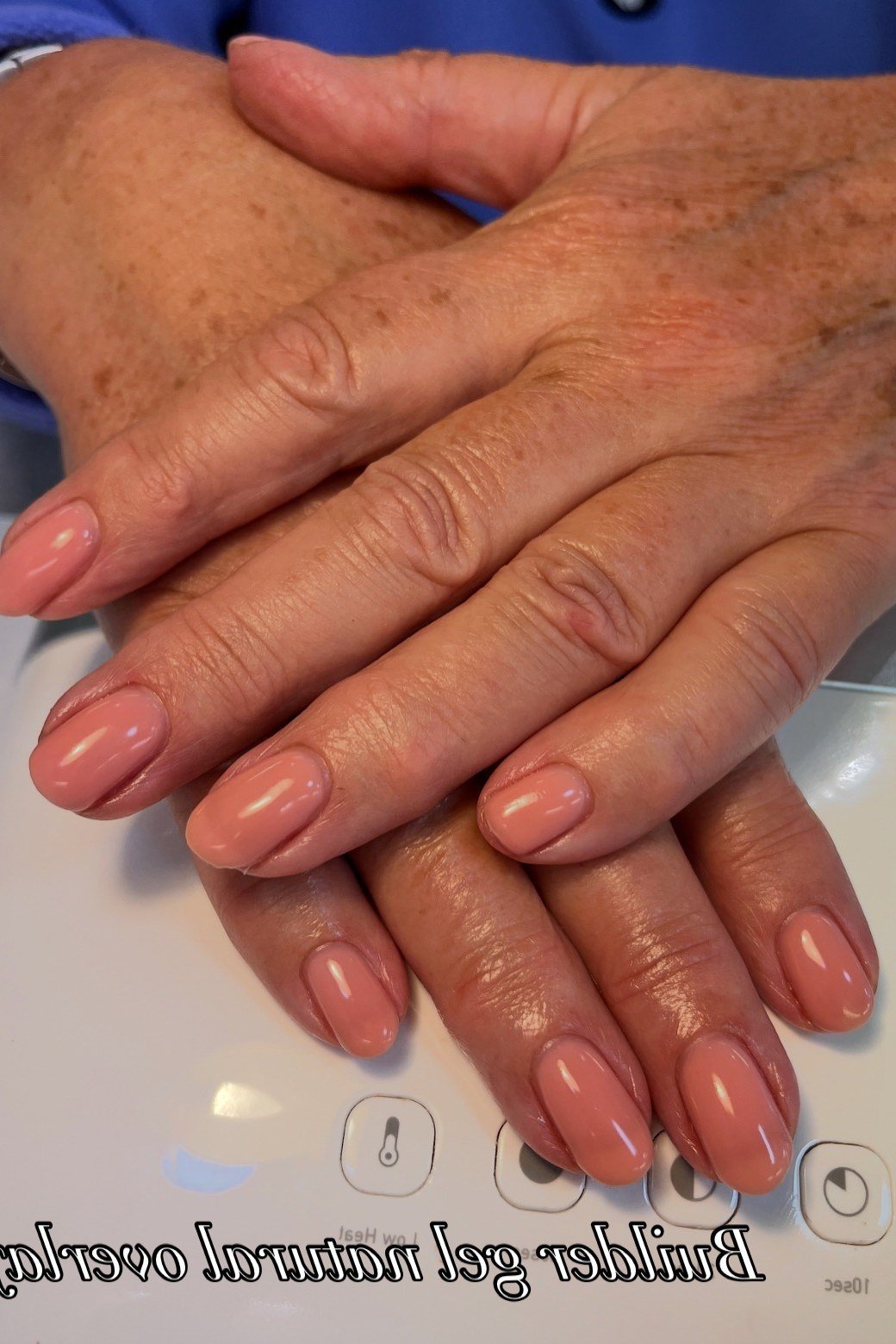Nude nails on mature crossed hands at salon, builder gel for women over 50